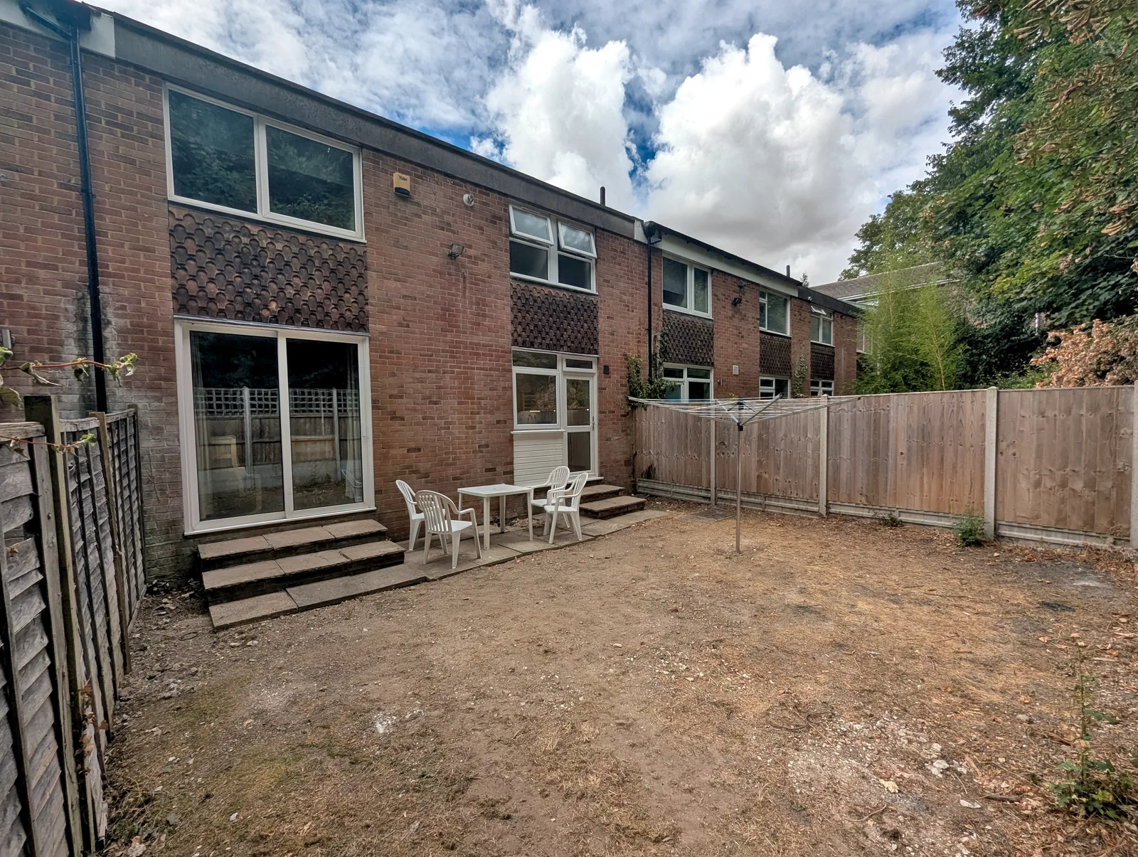 Rear garden with substantial fencing and mature trees beyond